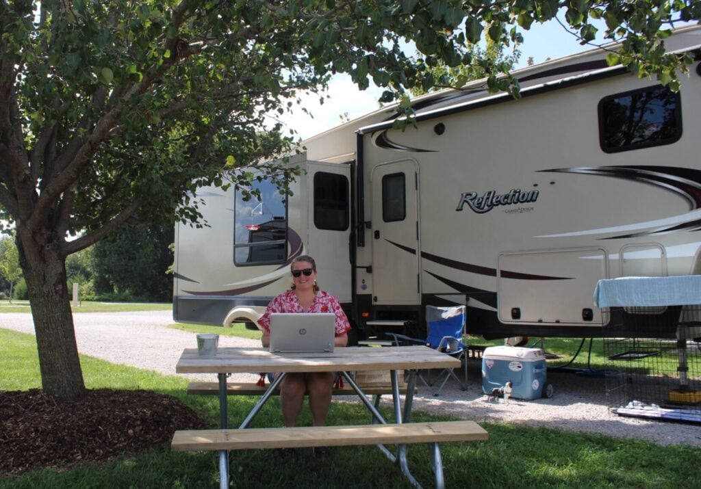 Woman on computer at picnic table at RV park.