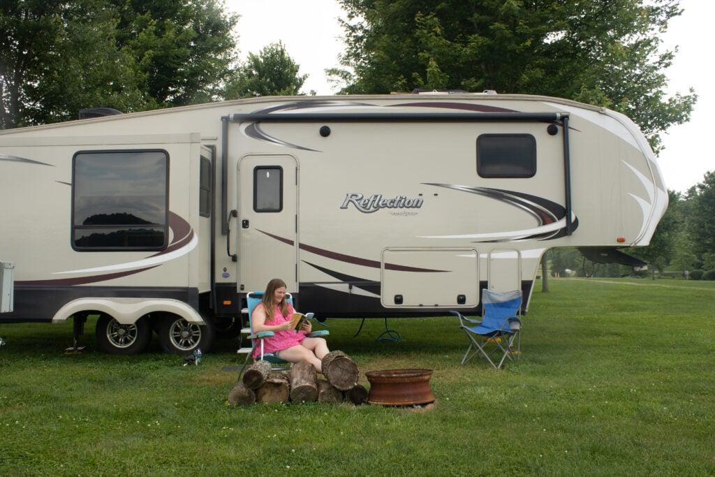 Woman reading book at campsite on RV road trip.