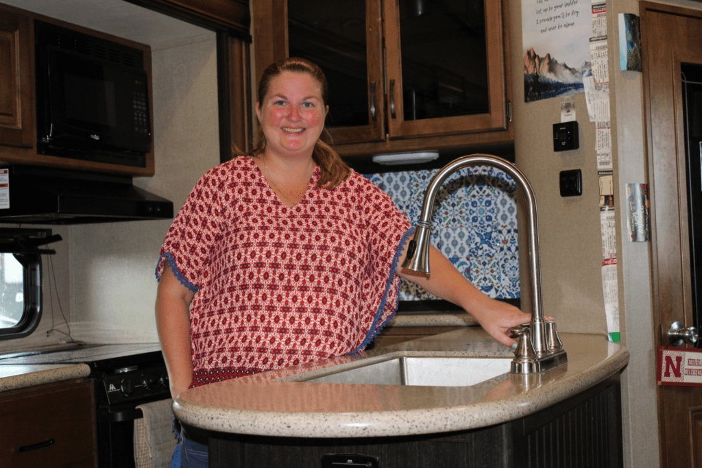 Woman using sink in RV kitchen.