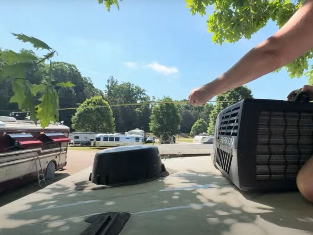 Woman on RV roof measuring height from roof top A.C.