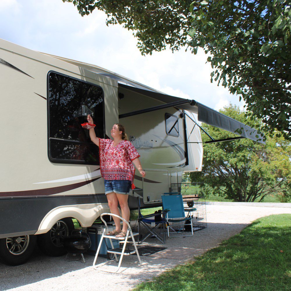 Woman decorating RV campsite with hummingbird feeder