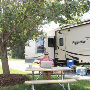 Woman sitting at picnic table with laptop at RV Campsite