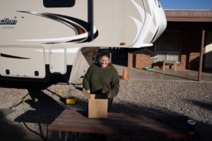 Woman opening mail package in front of RV>