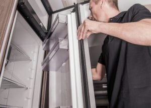 Man opening RV refrigerator.