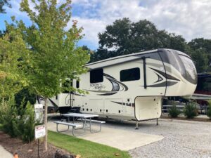 Gray and beige fifth wheel parked at RV park.