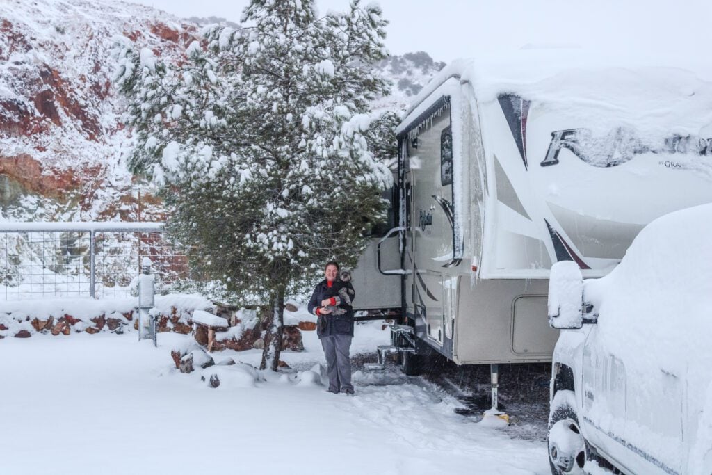 Woman standing in front of RV covered in snow in the winter