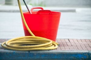 A red bucket and yellow garden hose.