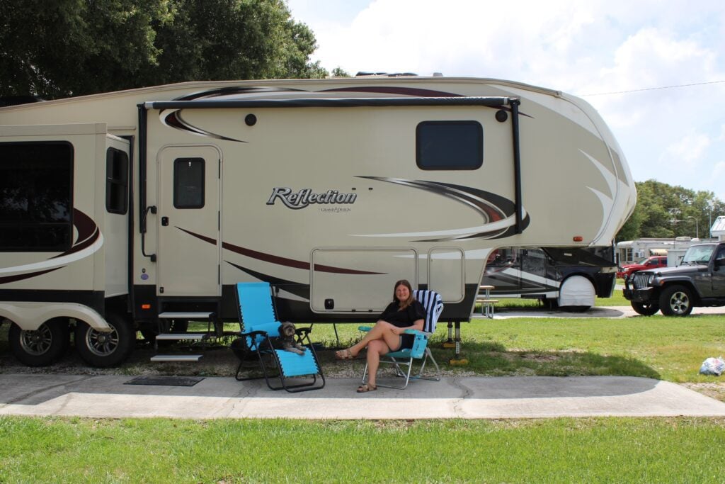 Woman sitting in blue chair outside fifth wheel RV