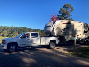 Man driving truck with fifth wheel RV hitched to it.