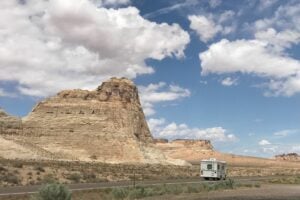 Class C RV driving down road beside limestone formations.