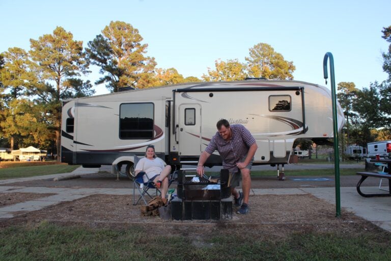 Couple sitting by fire in front of RV on a road trip