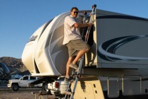 Mobile RV repairman on Ladder on side of Fifth Wheel RV