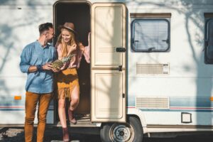 Happy couple standing outside RV door.