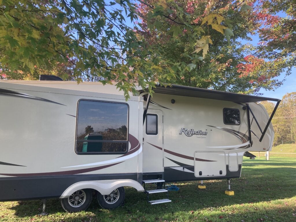 Fifth wheel RV with awning partially retracted.