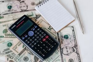 Calculator and notepad sitting on dollar bills.