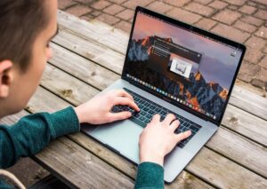 Man using laptop on picnic table.