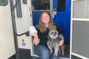 Woman holding the best RV Toilet paper. She is sitting on RV steps with dog.