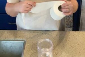 Putting sheets of toilet paper into jar in RV.