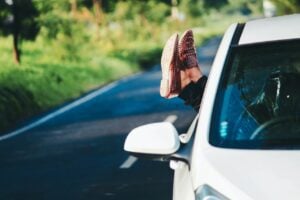 Woman's feet hanging out of car window.