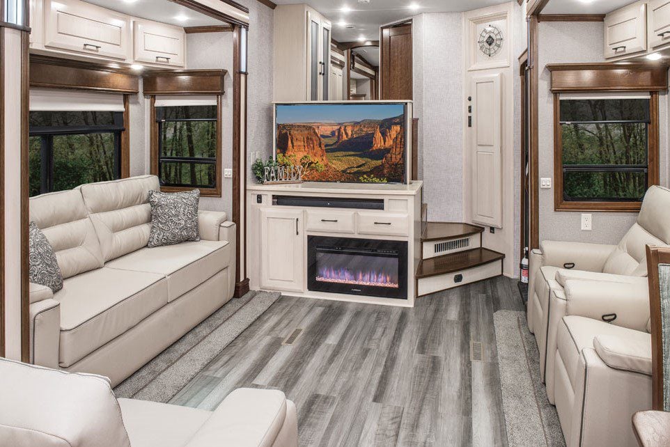 Interior of luxury RV with white couches and TV lifted out of cabinet. 