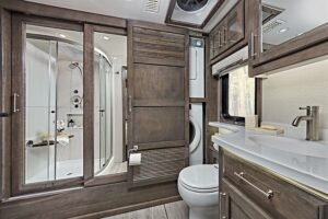 RV bathroom with large shower and laundry cabinet. 