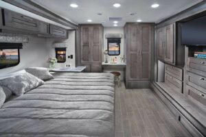 RV bedroom with large wood wardrobe and laundry cabinets. 