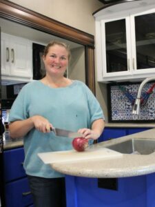 Woman chopping onion in RV kitchen.