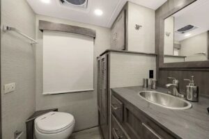 Bathroom in RV with toilet, sink and washer and dryer cabinet.