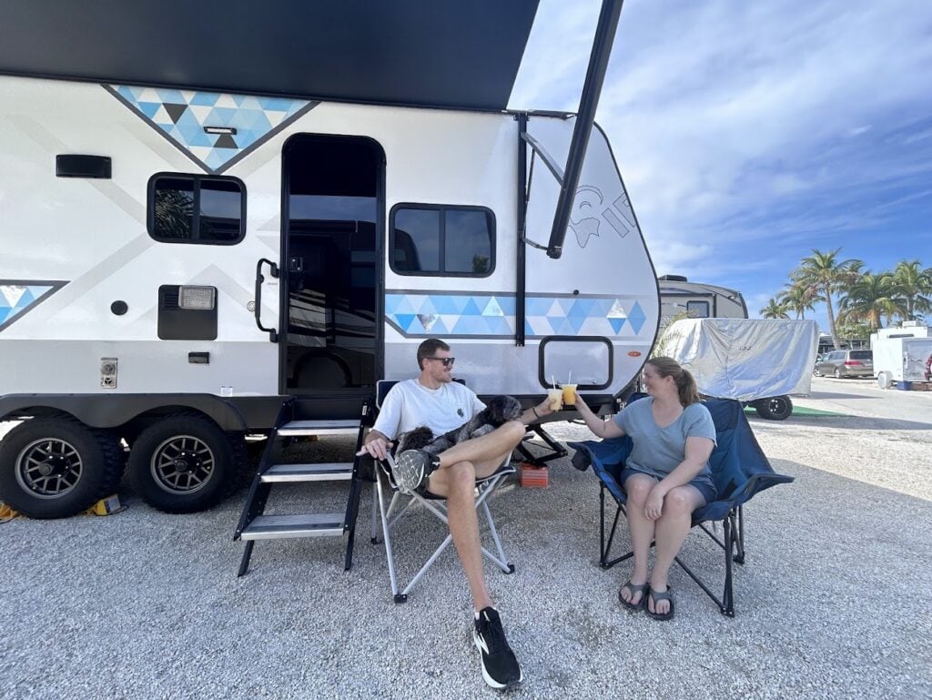 Couple cheersing with drinks at RV campsite.