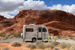 Molded fiberglass camper parked in front of red rocks.