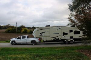 Fifth wheel RV being towed by white truck.