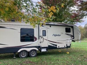 RV parked under tree with changing leaves.