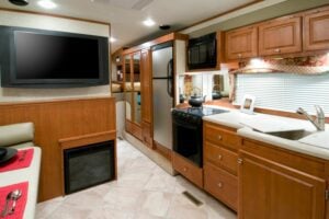 Interior of RV including TV, kitchen and refrigerator. 