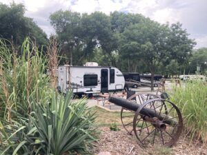 Small travel trailer parked at landscaped campsite.