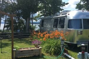 Airstream RV parked in waterfront campsite with flowers at adult only campground.