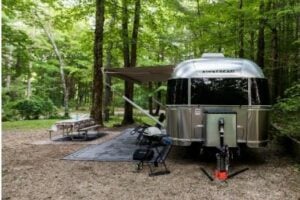 Airstream RV parked at wooded campsite.
