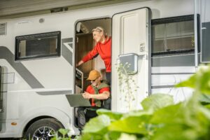 Couple in RV doorway using laptop computer.