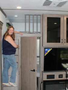 Woman on loft ladder in fifth wheel RV.