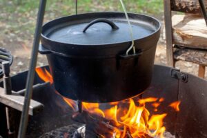Dutch oven on tripod over campfire.
