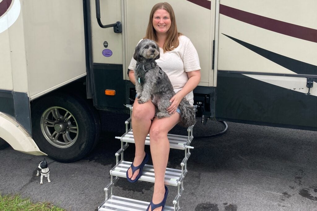 Woman sitting on upgraded RV stairs with small dog in lap.