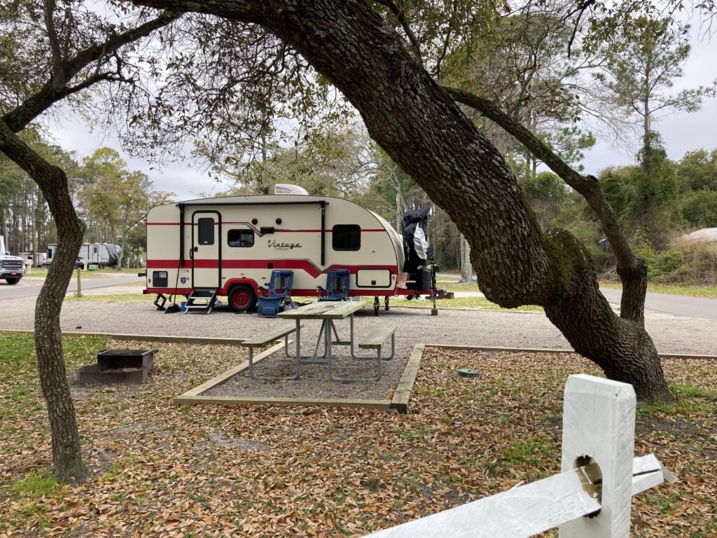 Vintage RV at pretty campsite with trees.