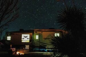 RV at night with bat Halloween decorations in window.