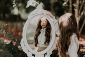 Spooky woman looking in antique mirror.