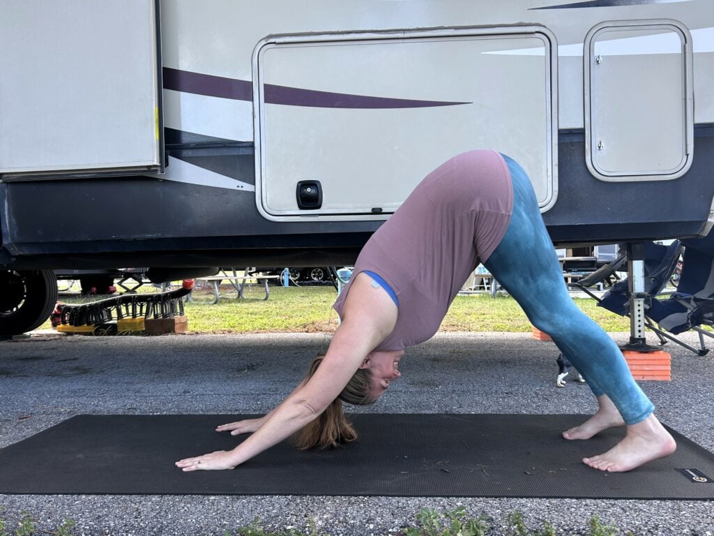 Woman doing downward dog yoga pose at RV campsite.