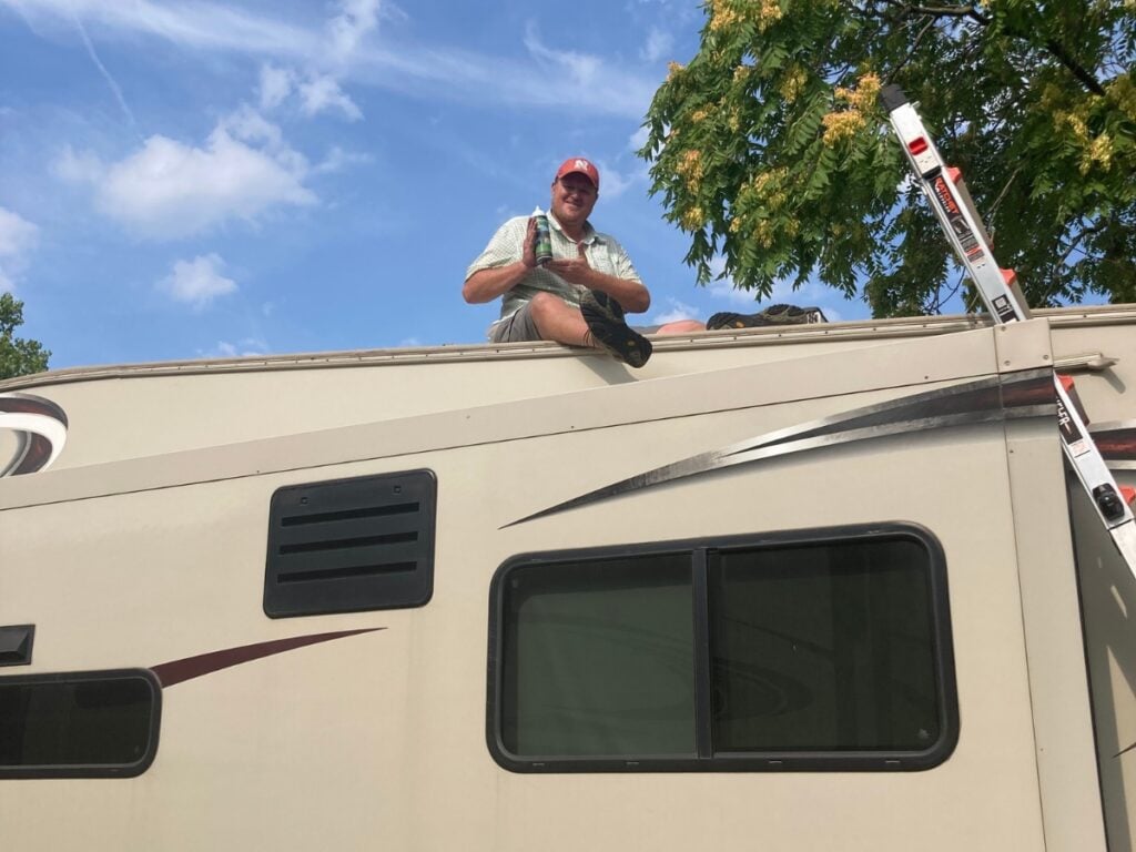 Man on RV roof to perform RV AC maintenance. 