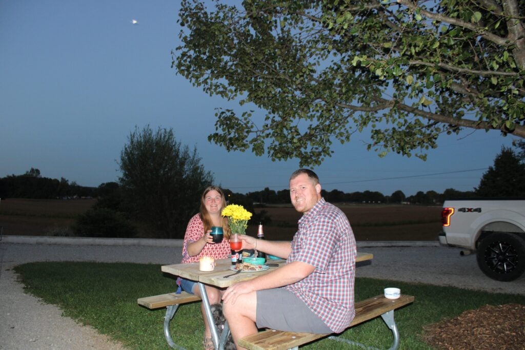 Couple eating dinner at RV campsite.