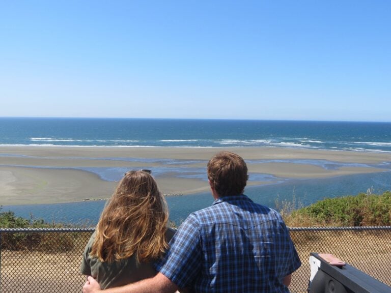 Couple sitting in truck bed overlooking ocean