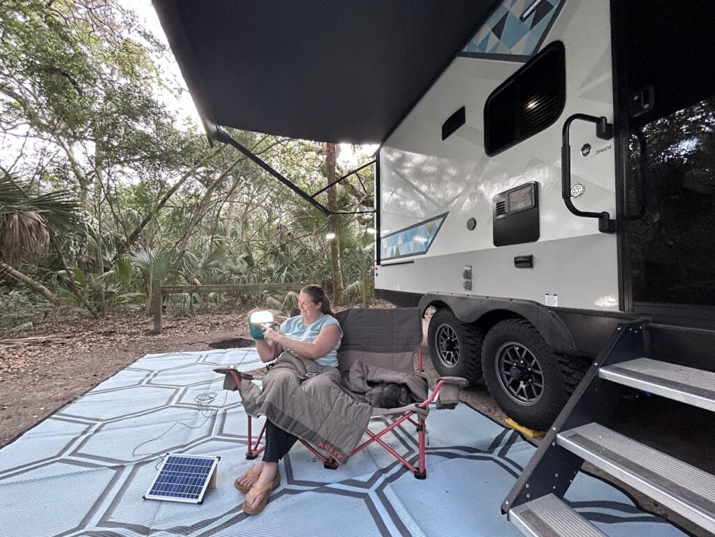 Woman holding solar controller at RV campsite.