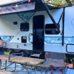 Man grilling and woman hitting ping pong ball at RV campsite party