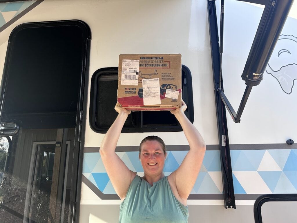 Woman holding box with Andersen Weight Distribution Hitch above her head.